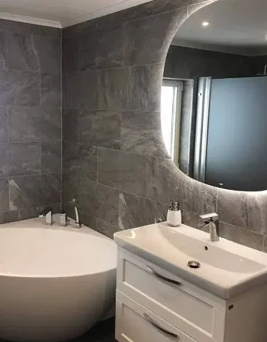 Nyrenoverat badrum med rund spegel, gjort av Jana Bygg AB